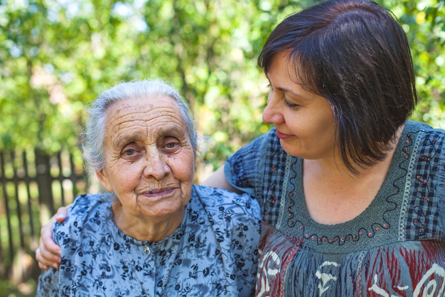 daughter puts arm around elderly mother