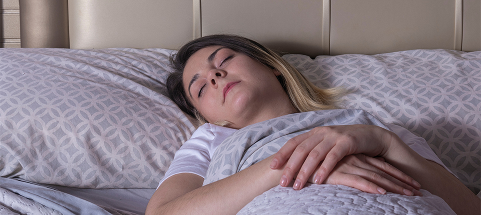 A woman sleeps on her back with help from mindfulness.