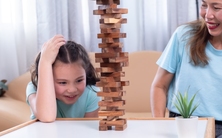 mother and daughter playing jenga on a table lessening screen time