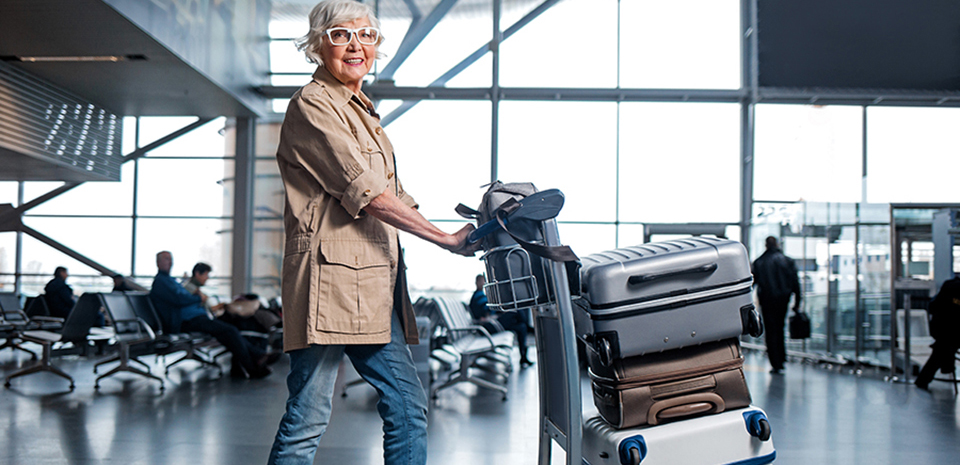 A woman pushes a cart with her luggage through an airport.