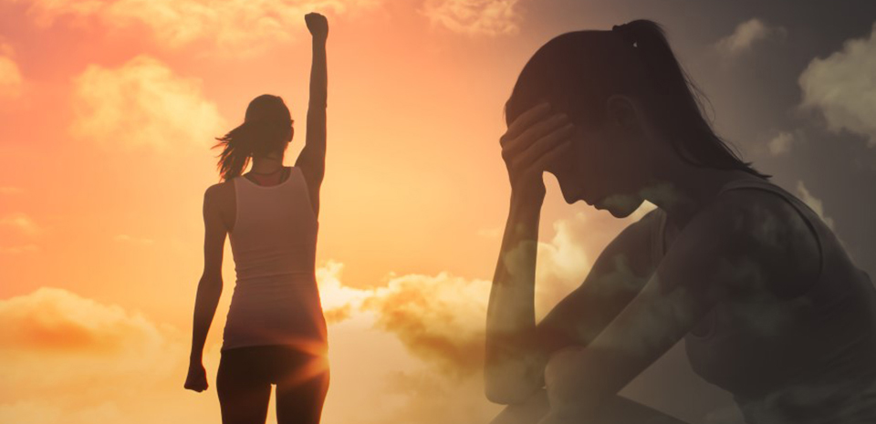 2 versions of a woman: One stands with arms raised in front of a vibrant sunset. The other is semi transparent of her silhouette, sitting down, head in hand.