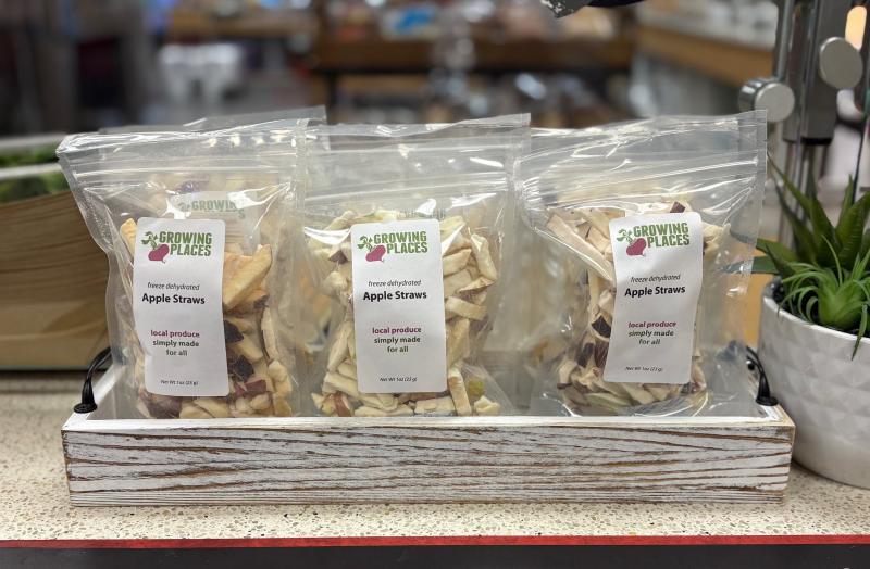 Bags of apple straws lined in a row. The bags read "Growing Places, freeze dehydrated Apple straws. Local produce simple made for all."