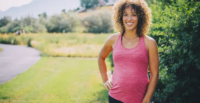 A pregnant woman visits the track in a park to get exercise.