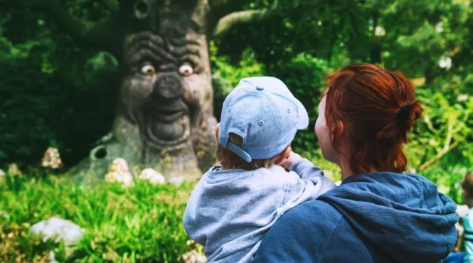 mom holding toddler near tree with a funny face sharing childhood myths
