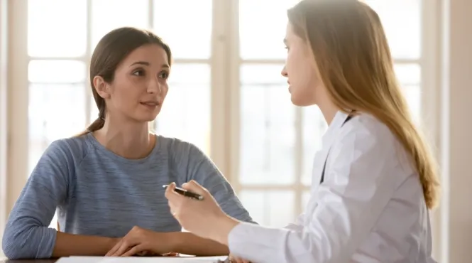 Woman with a genetic counselor at a desk talking about cancer genetic testing