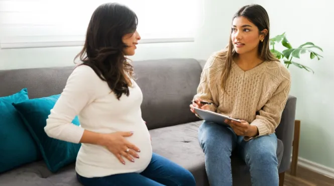 Pregnant woman with a doula sitting on a couch preparing for childbirth.