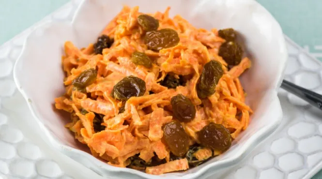 carrot and raisin slaw in a white serving bowl