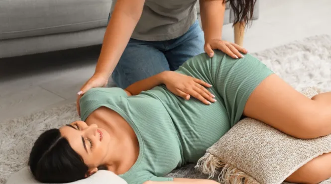 Doula relieving pregnancy stress by giving a massage to a woman 