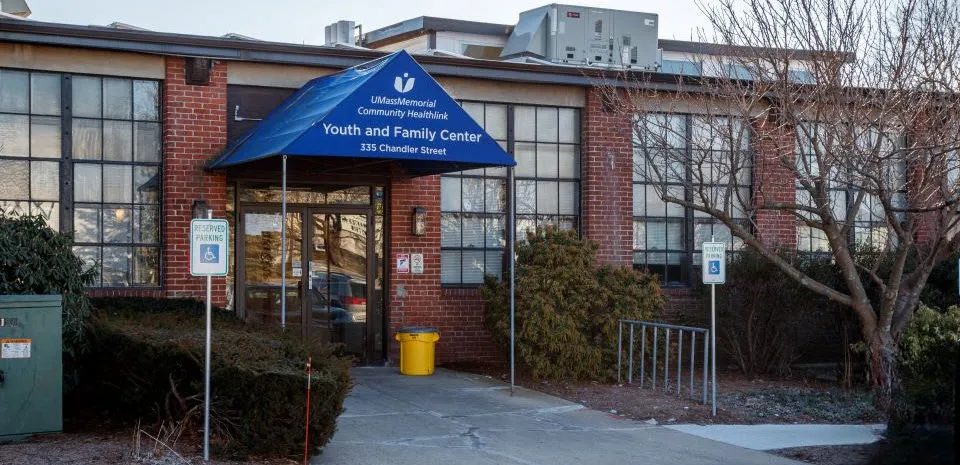 A blue awning is over the entrance of a red brick building, the Community Healthlink, Inc. - Youth and Family Behavioral Health Services at 355 Chandler Street in Worcester.