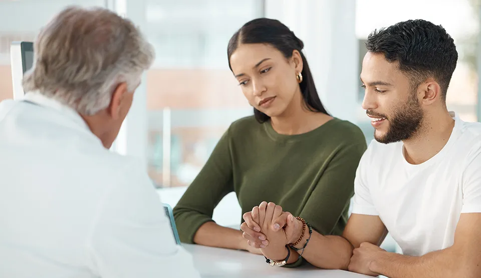 Two parents talking to a doctor while looking at a monitor.
