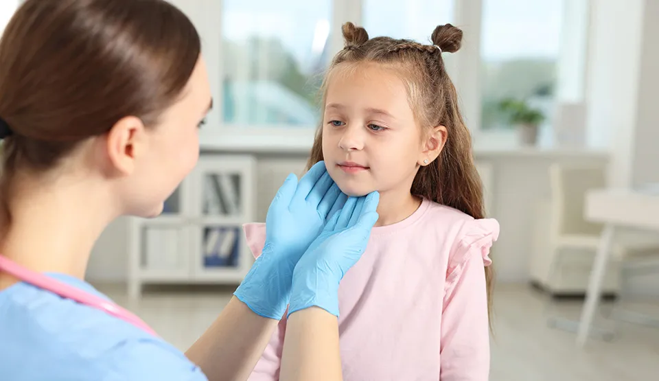 A caregiver wearing gloves and checking a child's neck