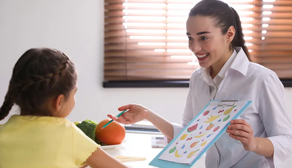 A doctor showing a child patient a chart of fruits and vegetables.