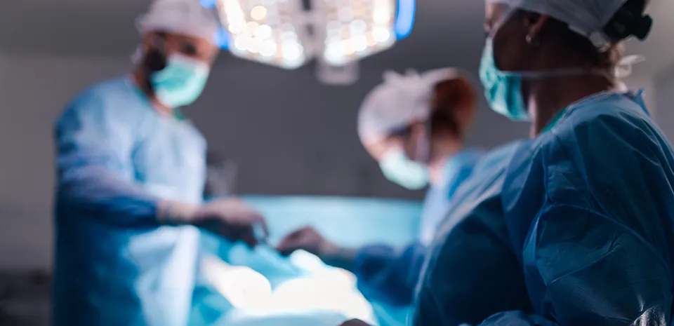 A team of surgeons in blue scrubs and masks work together during a delicate operation, with surgical instruments neatly arranged on the table under bright operating room lights.