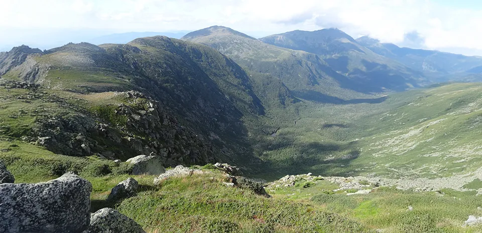 A large green valley is shown from atop a mountain on the Jewell Trail in the Presidential Range of the White Mountains.