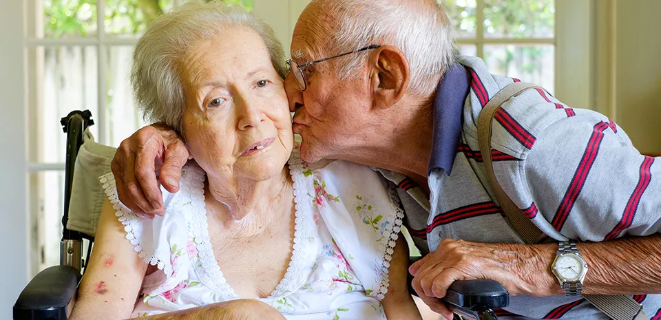 elderly man kissing his wife on the cheek