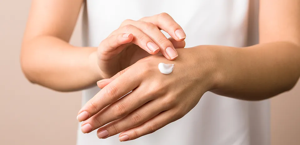 person putting on hand lotion