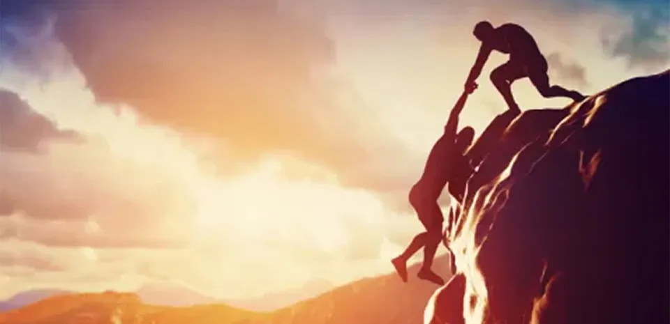 man helps other man that is falling off a cliff