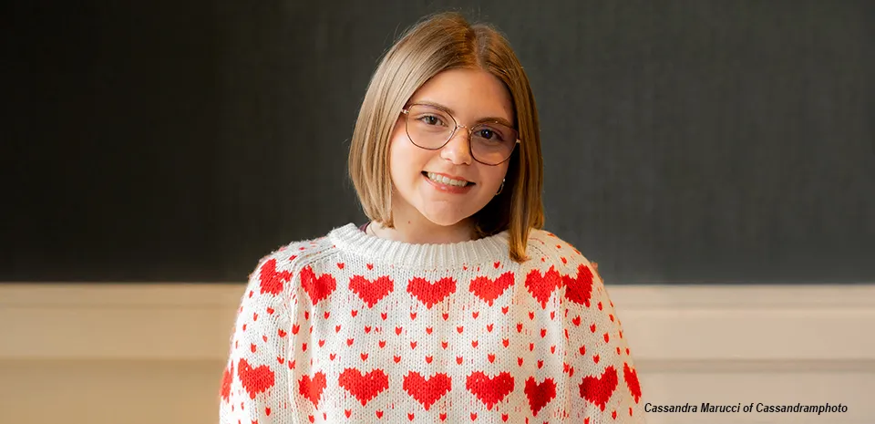 Adelaide Greenwald, looking at the camera, wearing a white sweater with a red heart pattern.