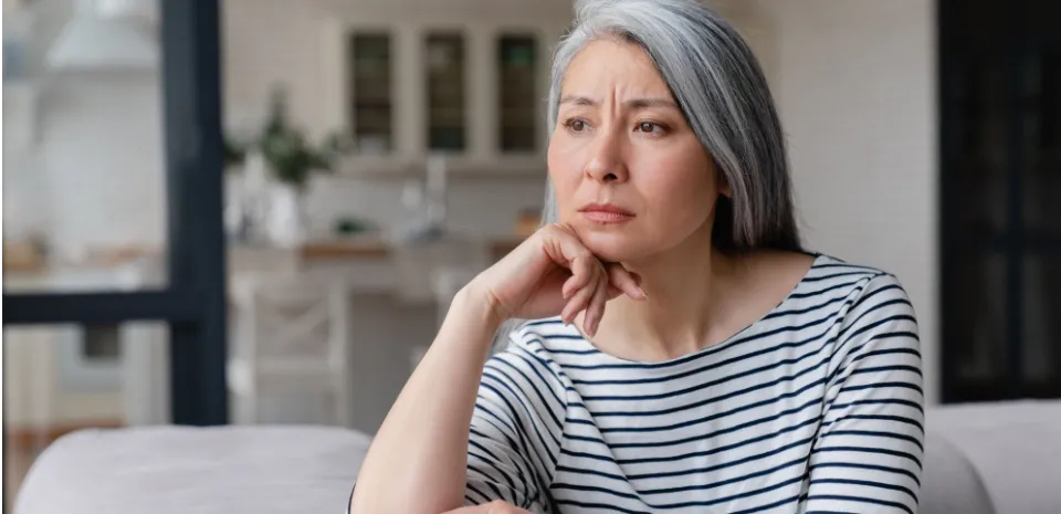 A sad woman staring on a couch needing to improve her mental health