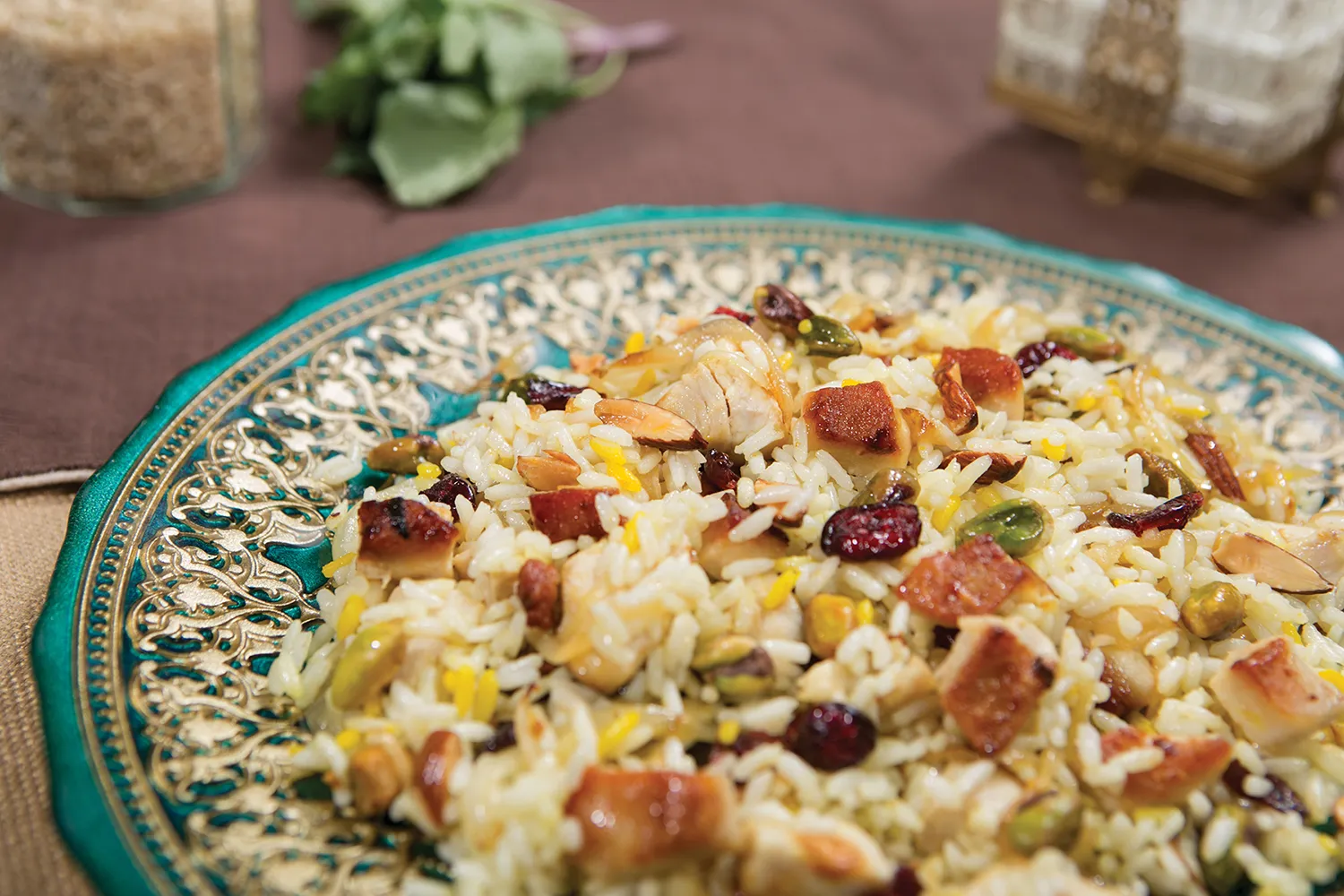 A colorful teal and gold plate holds a rice dish with barberries.
