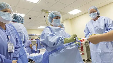 Caregivers assist each other with protective gear.