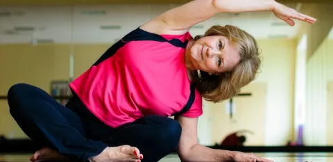 Woman sitting on a floor feeling the benefits of stretching