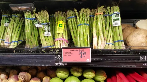 Bunches of asparagus are shown on a store shelf.