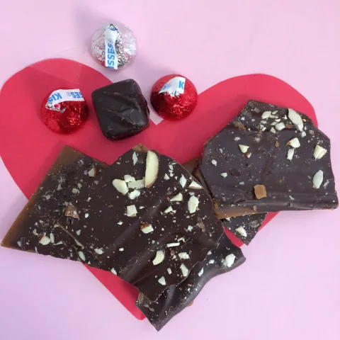 Chocolates and candies are shown on top of a red Valentine's heart.