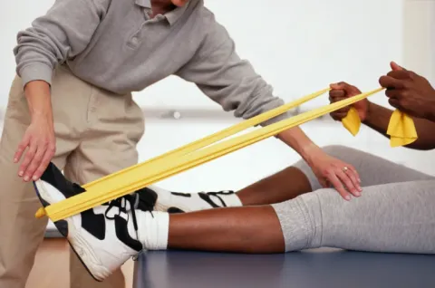 A physical therapist is helping someone use resistance bands.
