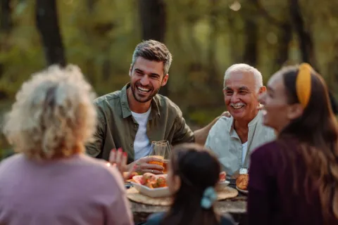 A group of adults are sitting around a picnic.