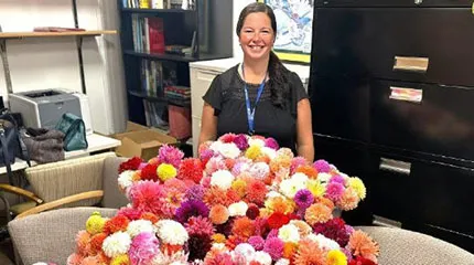 Sarah Skinner stands behind the dahlias she will distribute to patients at UMass Memorial Medical Center.