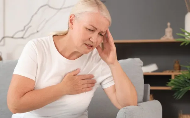 woman on couch holding sore arm caused by lymphedema after cancer.