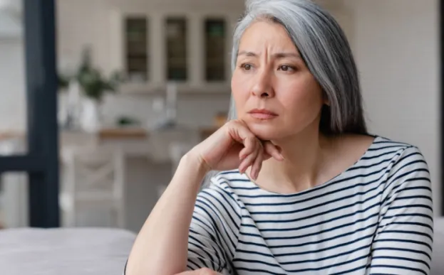 A sad woman staring on a couch needing to improve her mental health