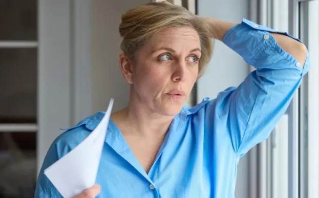 A woman having a hot flash fanning herself trying to manage menopause symptoms