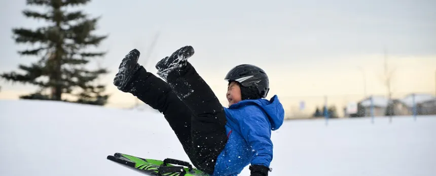 boy wearing helmet sledding following winter safety tips