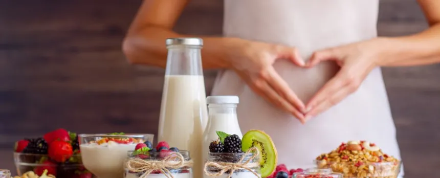 Woman with dysbiosis in front of table of food making a heart with her hands