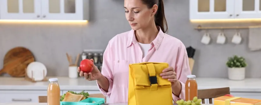 Woman at a kitchen counter prepping her lunch with healthy foods 