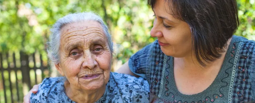daughter puts arm around elderly mother