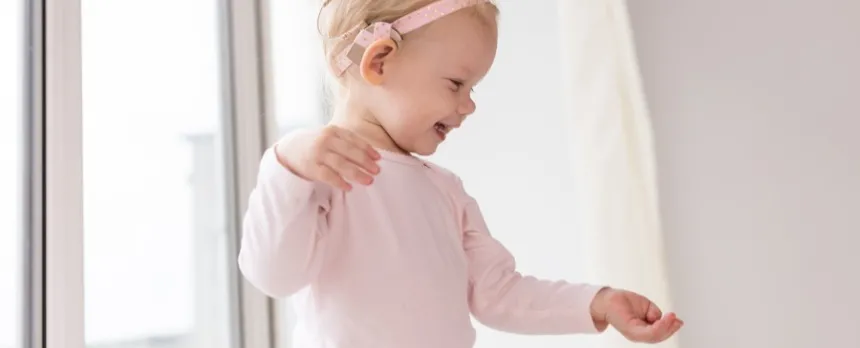 Toddler girl with cochlear implant smiling as she is discovering the world around her
