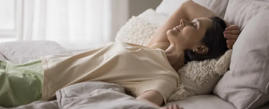 a woman lying comfortably in bed performing a body scan for mindfulness