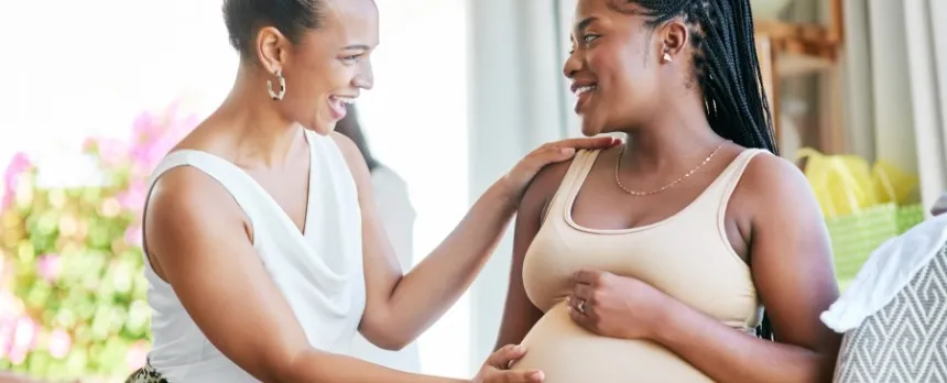 Doula with hand on smiling pregnant woman's tummy