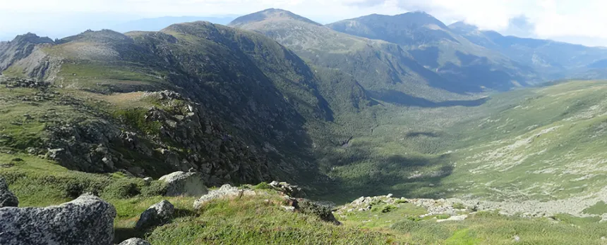 A large green valley is shown from atop a mountain on the Jewell Trail in the Presidential Range of the White Mountains.