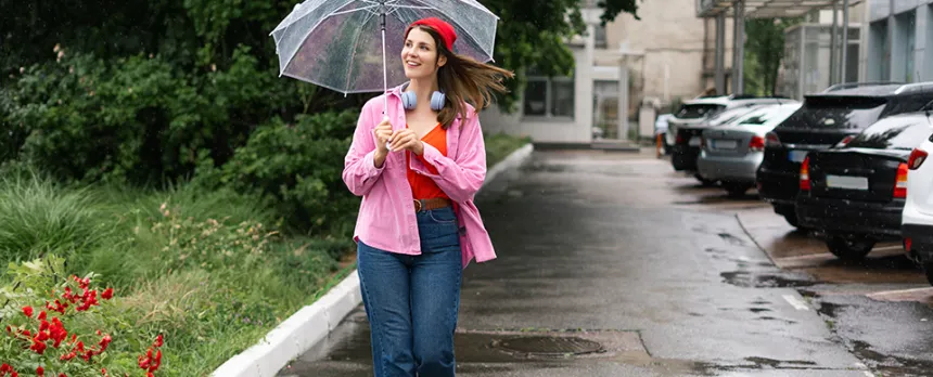 woman walking down the road with umbrella while it is raining