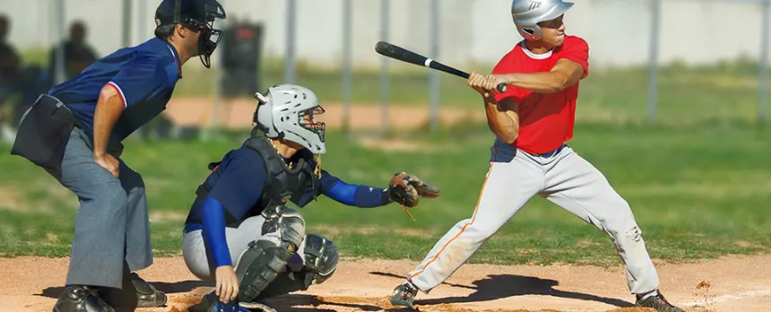 A batter is ready to swing at home plate with the umpire and catcher ready to participate in the play.